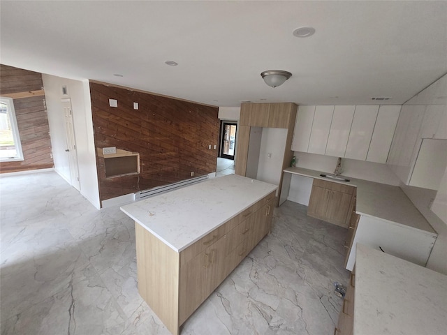 kitchen featuring a healthy amount of sunlight, wooden walls, modern cabinets, and marble finish floor