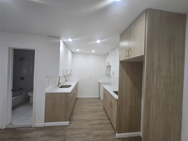 kitchen featuring recessed lighting, a sink, baseboards, light countertops, and wood finished floors