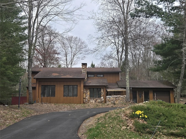 prairie-style home featuring a chimney, stone siding, aphalt driveway, and an attached garage