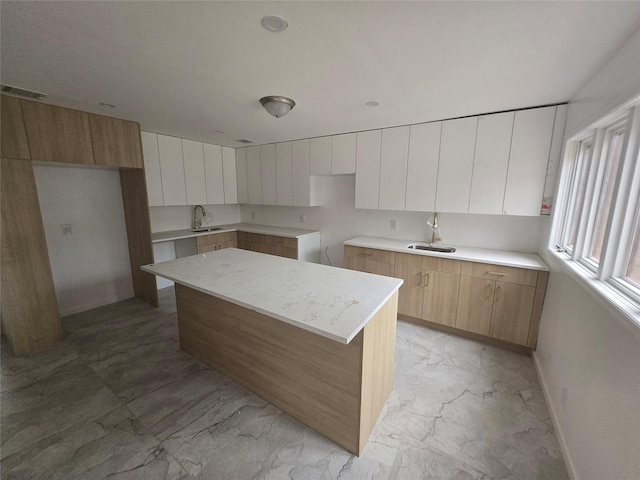 kitchen with a sink, marble finish floor, modern cabinets, and visible vents