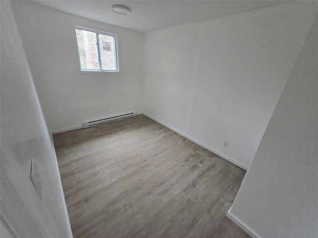 spare room featuring baseboards, a baseboard radiator, and wood finished floors