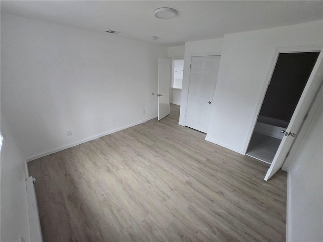 unfurnished bedroom with baseboards, wood finished floors, and visible vents