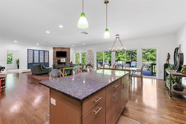 240 Brady Rd, Warwick, NY 10990 - kitchen featuring a stone fireplace, a center island, wood finished floors, decorative light fixtures, and dark stone counters