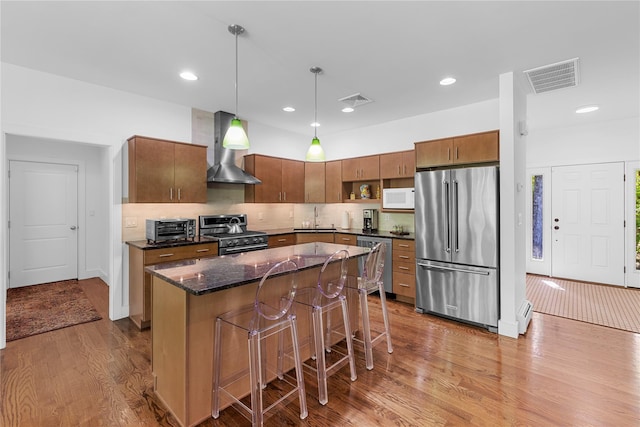 240 Brady Rd, Warwick, NY 10990 - kitchen featuring stainless steel appliances, wall chimney exhaust hood, a sink, wood finished floors, and a breakfast bar