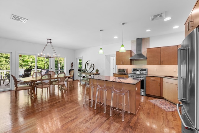 240 Brady Rd, Warwick, NY 10990 - kitchen featuring stainless steel appliances, wall chimney exhaust hood, brown cabinetry, wood finished floors, and a kitchen island