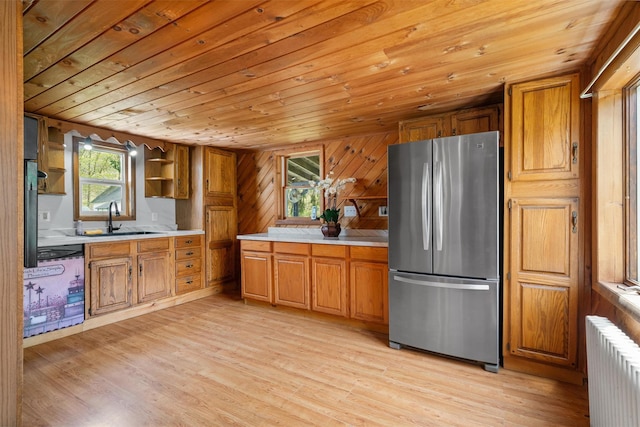 kitchen with a sink, radiator, brown cabinets, freestanding refrigerator, and wooden ceiling