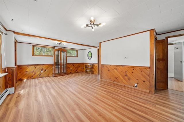 empty room with wood walls, light wood-style flooring, wainscoting, and ornamental molding