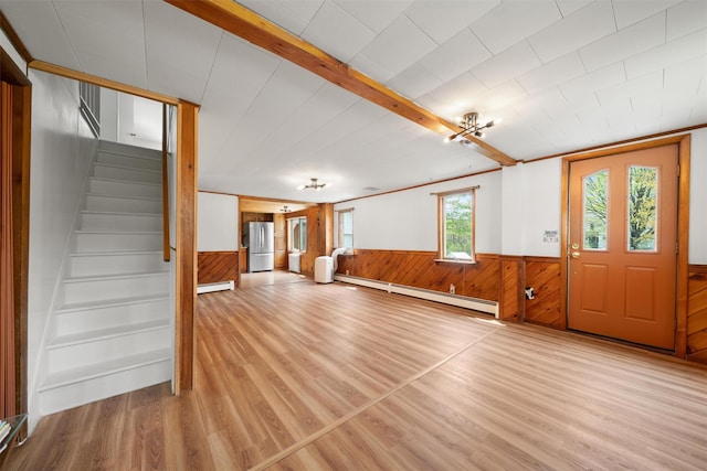 entryway featuring a baseboard radiator, stairs, wooden walls, a wainscoted wall, and wood finished floors
