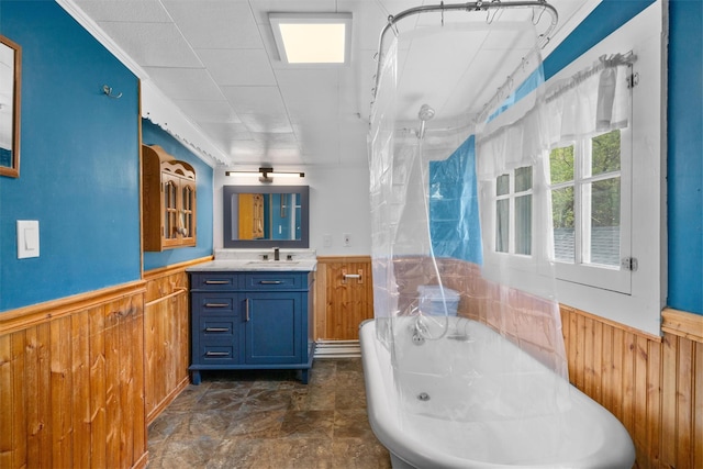 bathroom featuring wood walls, wainscoting, and a freestanding bath