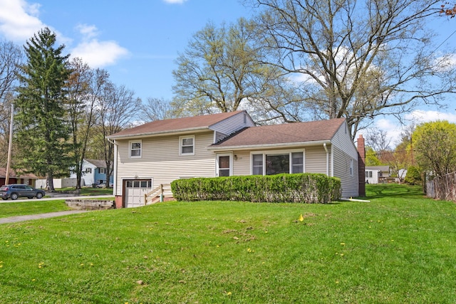 tri-level home with a front yard, a garage, and driveway