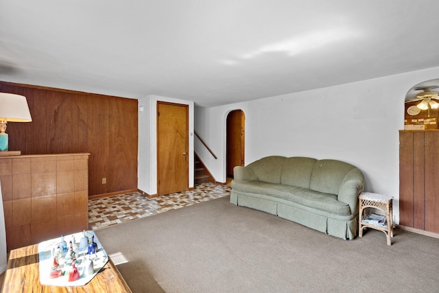 living area featuring arched walkways, carpet flooring, stairway, and baseboards