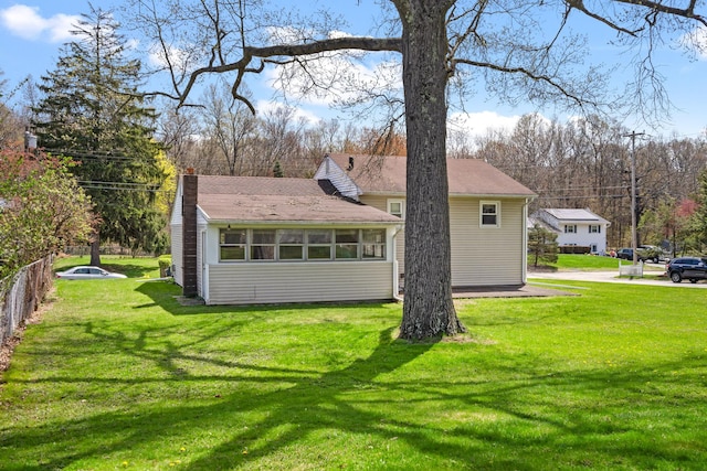 view of side of property with a chimney and a lawn