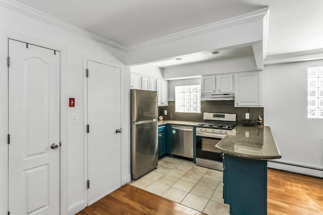 kitchen with a peninsula, stainless steel appliances, white cabinetry, under cabinet range hood, and a baseboard radiator