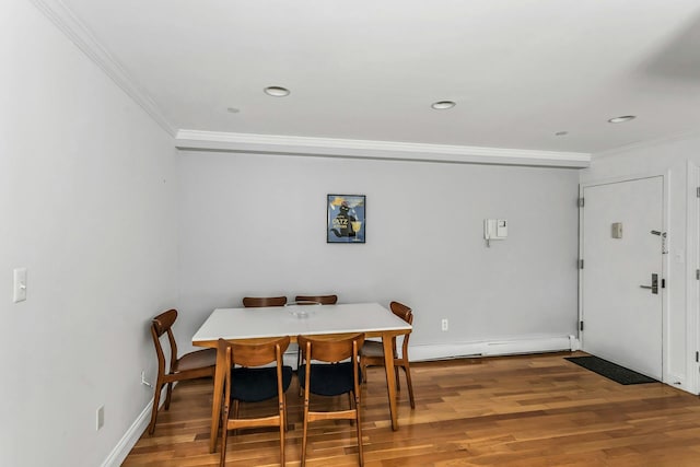 dining room with recessed lighting, a baseboard heating unit, baseboards, crown molding, and wood finished floors
