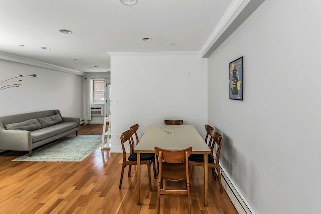 dining room with crown molding, baseboards, baseboard heating, and wood finished floors