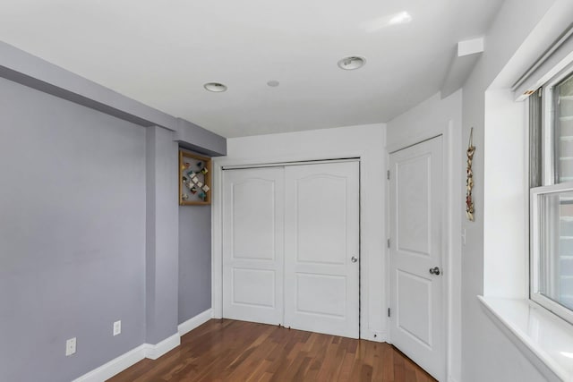 unfurnished bedroom with baseboards, dark wood-style flooring, a closet, and recessed lighting