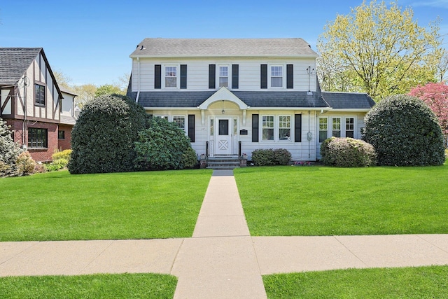 view of front facade featuring a shingled roof and a front lawn