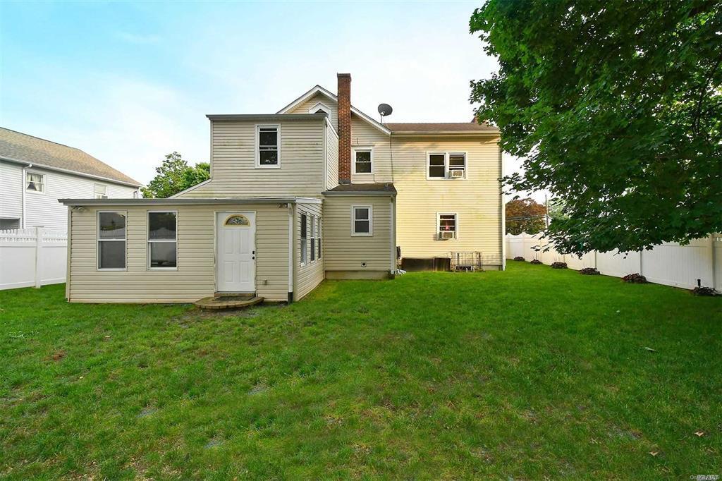 rear view of house with a lawn, a chimney, and a fenced backyard
