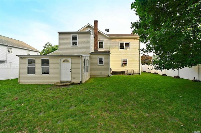 rear view of house with a lawn, a chimney, and a fenced backyard