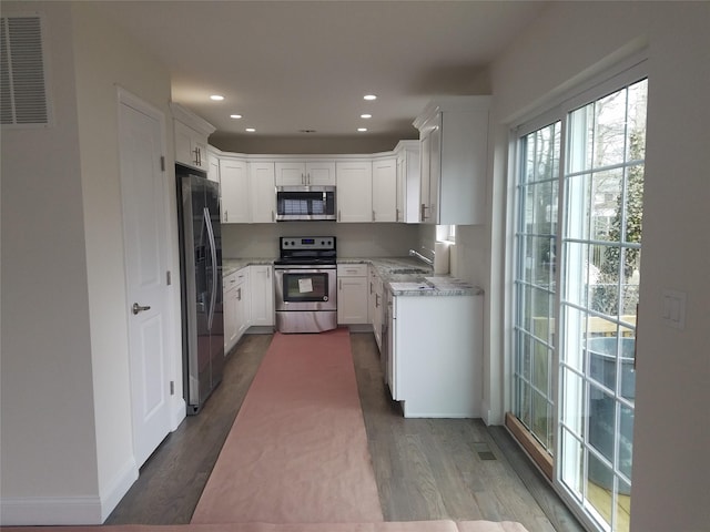 kitchen featuring visible vents, white cabinetry, stainless steel appliances, and dark wood-type flooring