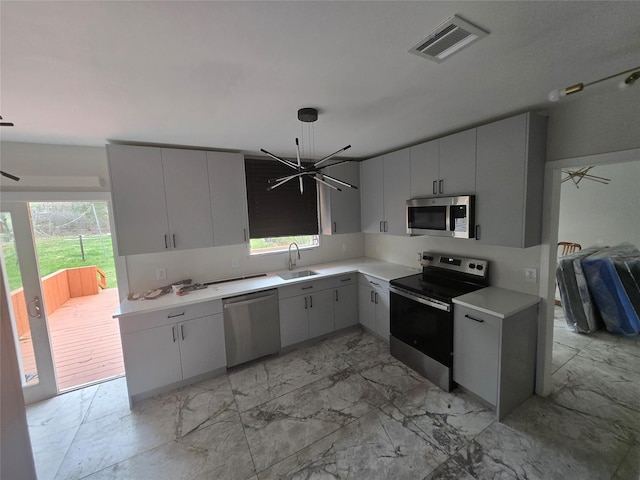kitchen with stainless steel appliances, light countertops, marble finish floor, a sink, and visible vents