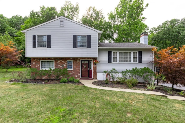 split level home with a front lawn, a chimney, and brick siding