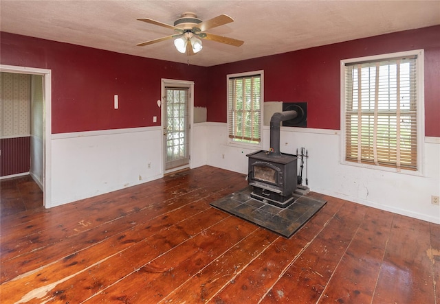 1603 Goshen Tpke, Middletown, NY 10941 - unfurnished living room featuring a wainscoted wall, wood-type flooring, a wood stove, and a ceiling fan