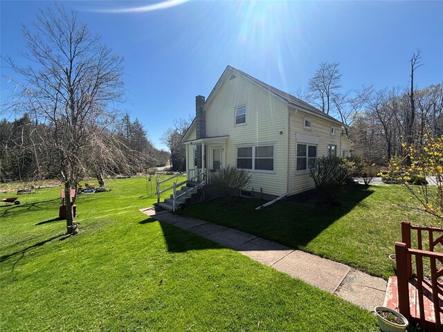 view of side of property featuring a chimney and a lawn