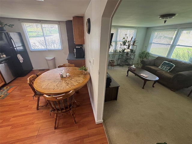 dining area with light wood-style floors, a healthy amount of sunlight, and arched walkways