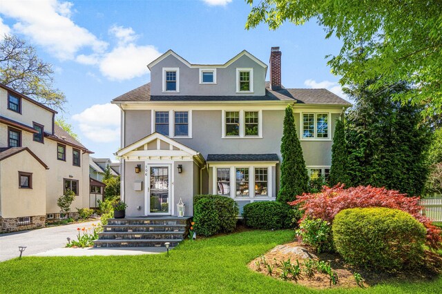 view of front of home with a chimney, a front yard, and stucco siding
