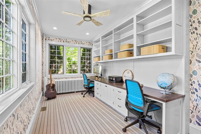 carpeted office space featuring visible vents, ornamental molding, radiator, built in study area, and a ceiling fan