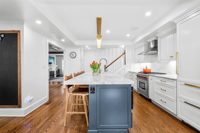 kitchen featuring an island with sink, wall chimney exhaust hood, white cabinets, dark wood finished floors, and high end stainless steel range oven