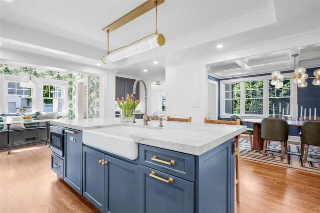 kitchen featuring plenty of natural light, a sink, ornamental molding, and blue cabinetry
