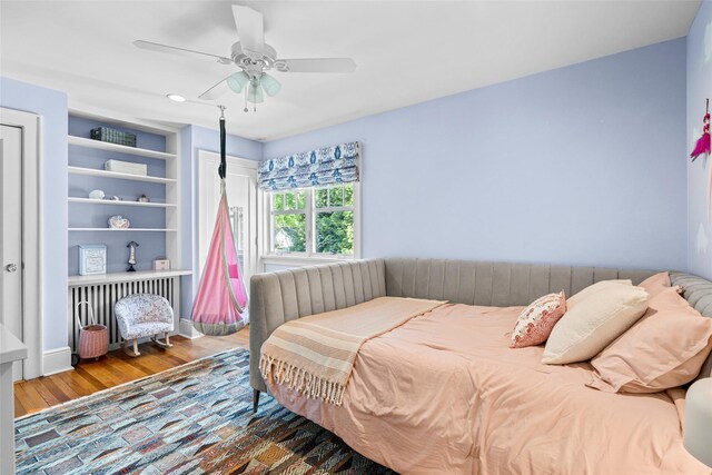 bedroom with a ceiling fan, recessed lighting, wood finished floors, and radiator
