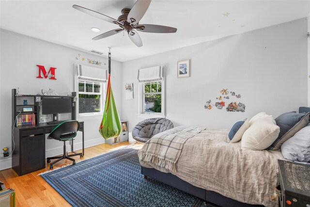 bedroom with ceiling fan, visible vents, and wood finished floors