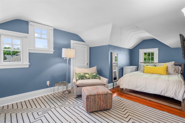 bedroom with baseboards, wood finished floors, and lofted ceiling