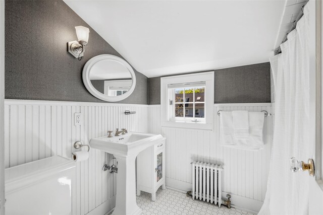 full bathroom featuring wainscoting, radiator heating unit, and lofted ceiling