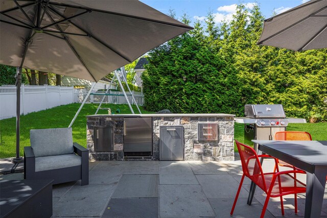 view of patio / terrace with an outdoor kitchen, grilling area, outdoor dining space, and a fenced backyard
