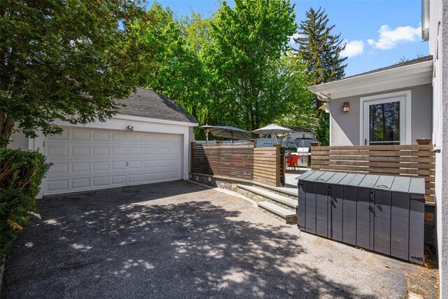 view of side of property with a garage, an outdoor structure, stucco siding, and driveway