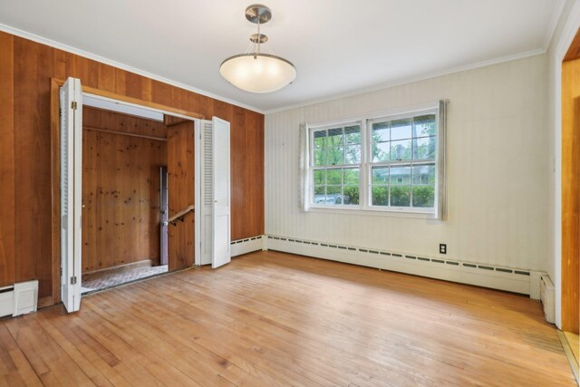 54 Cedar St, Stony Brook, NY 11790 - empty room featuring crown molding, light wood-style flooring, a baseboard radiator, and wooden walls
