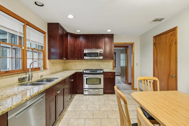 54 Cedar St, Stony Brook, NY 11790 - kitchen featuring appliances with stainless steel finishes, a sink, backsplash, reddish brown cabinets, and light stone countertops