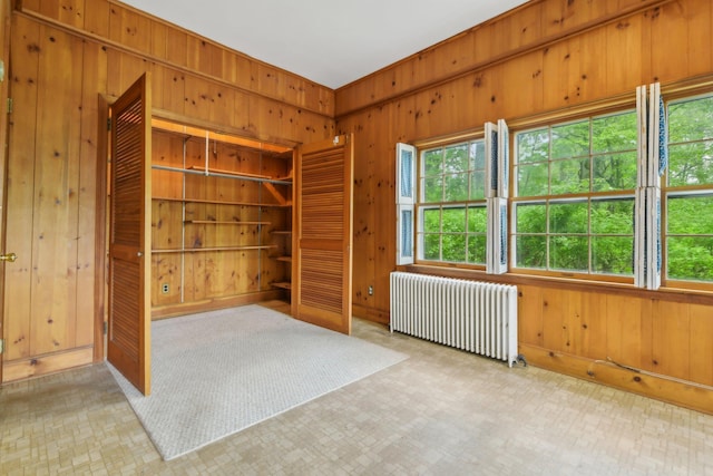 54 Cedar St, Stony Brook, NY 11790 - unfurnished bedroom with radiator heating unit, wooden walls, a closet, and multiple windows
