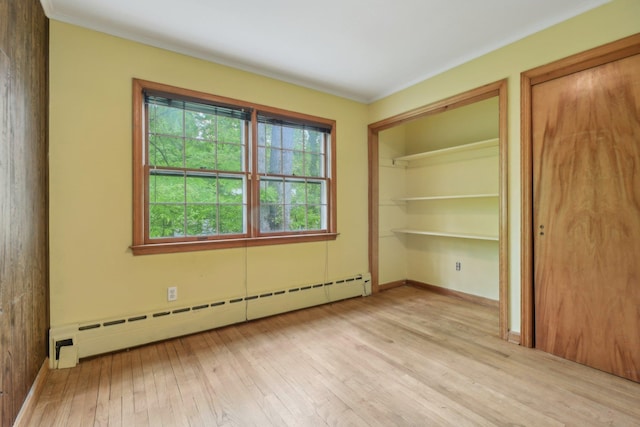 54 Cedar St, Stony Brook, NY 11790 - unfurnished bedroom with baseboard heating, light wood finished floors, two closets, baseboards, and crown molding
