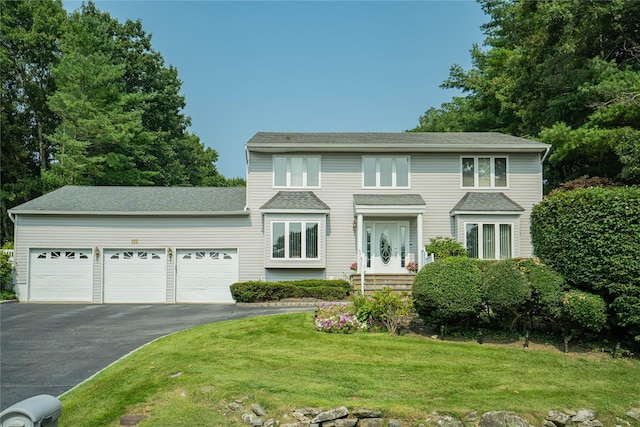 colonial-style house featuring an attached garage, driveway, and a front lawn