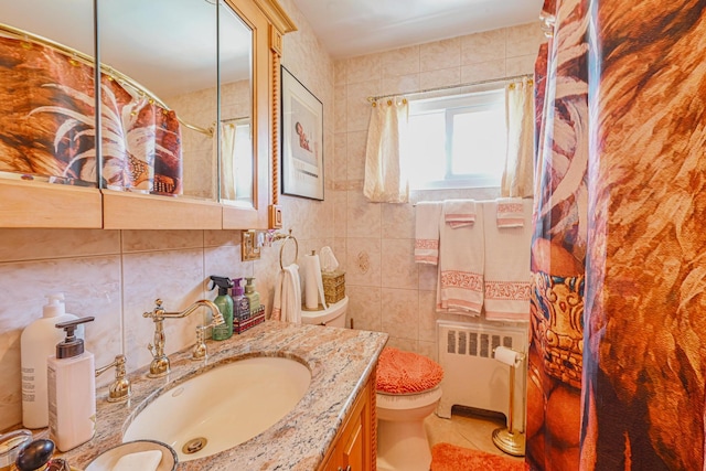 bathroom featuring vanity, toilet, tile walls, radiator heating unit, and tile patterned floors