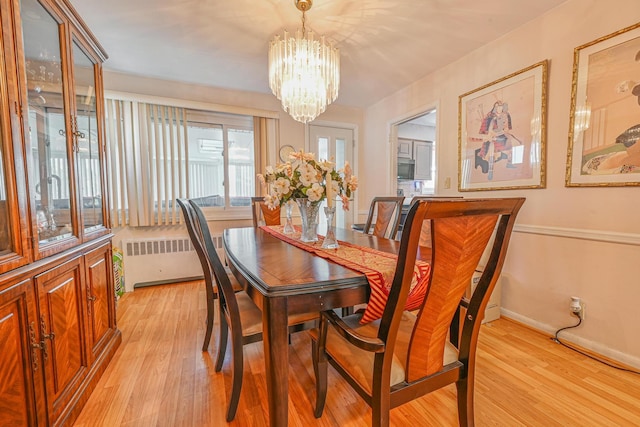 dining room featuring radiator heating unit, baseboards, light wood-style floors, and a notable chandelier