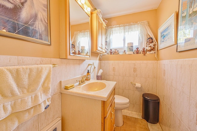 bathroom with vanity, a wainscoted wall, toilet, and tile walls