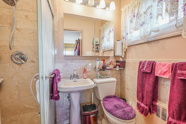 full bathroom featuring toilet, tile walls, a wainscoted wall, and a shower