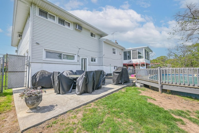 back of house featuring a gate, a sunroom, fence, a fenced in pool, and a yard