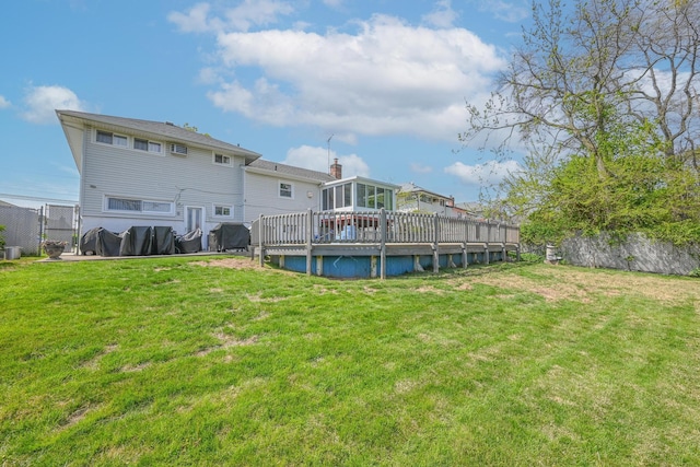 back of property with a lawn, a sunroom, fence, and a deck